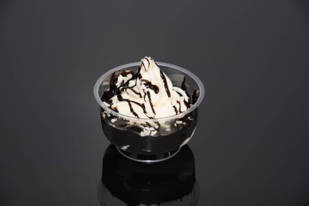 a sundae with vanilla ice cream and sauce on a dark baseの写真素材