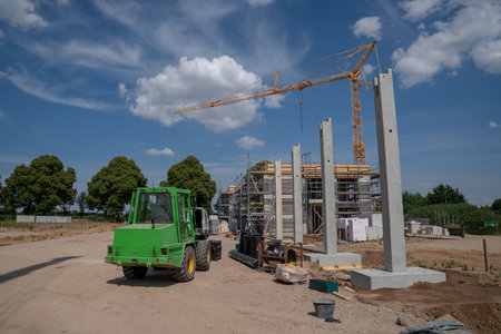 on a construction site, concrete columns for a factory building are placed with the help of a large...