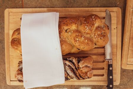 on a wooden board lie two different kinds of bread and next to it is a long bread knifeの写真素材