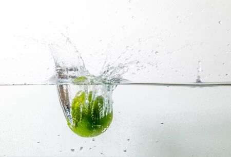 a lime falls into the water from above and creates water splashesの写真素材