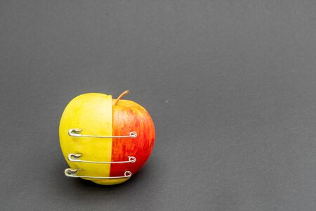 two different apple halves are held together with three safety pinsの写真素材