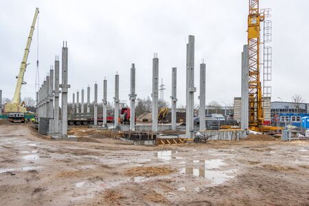 On a large construction site many concrete columns are placed with the help of a craneの写真素材