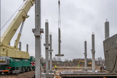 On a large construction site many concrete columns are placed with the help of a crane