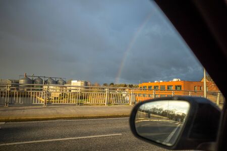 from the side window of a moving car you can see a rainbow in the skyの写真素材