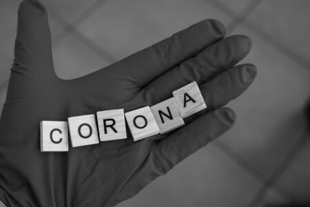 a hand with a glove on holds  bricks, which form the word: Corona