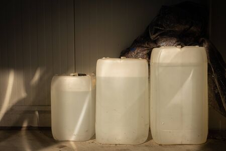 three filled white canisters of different sizes standing on a wall in a workshop