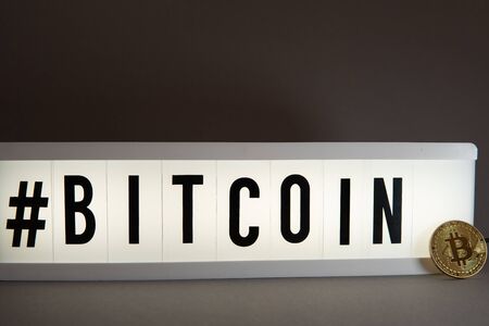 a golden Bitcoin coin stands in front of an illuminated panel with the inscription #Bitcoinの写真素材