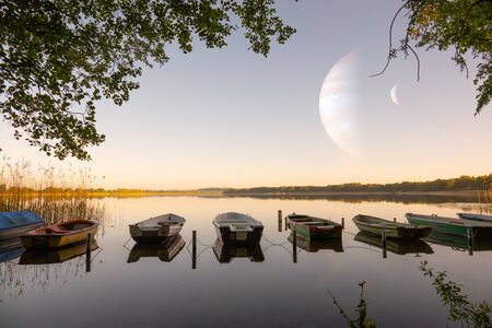 Rowing boats lie next to each other on the shore of a lake in completely calm water