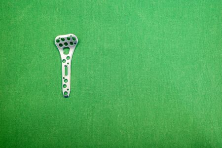 a titanium plate for a radius fracture lies on a green surgical drape