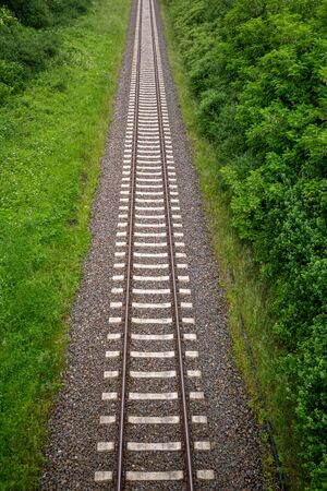 Railway tracks on a railway track bed lead through the picture