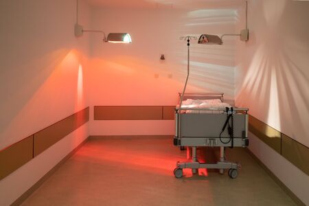 in one corner of an operating theatre, beds are warmed with a heat lamp