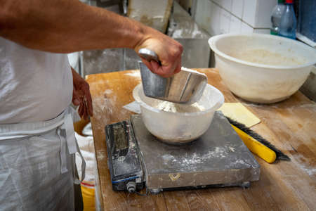 in a bakery a baker mixes the ingredients for a bread doughの写真素材