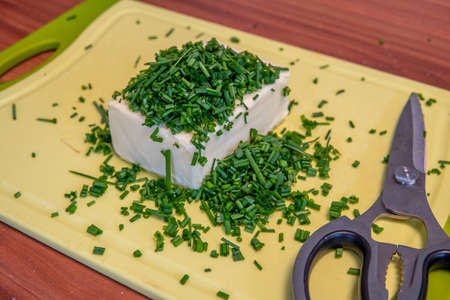 on a cutting board lie butter, chives and scissors to prepare herb butterの写真素材