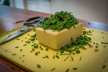 on a cutting board lie butter, chives and scissors to prepare herb butterの写真素材