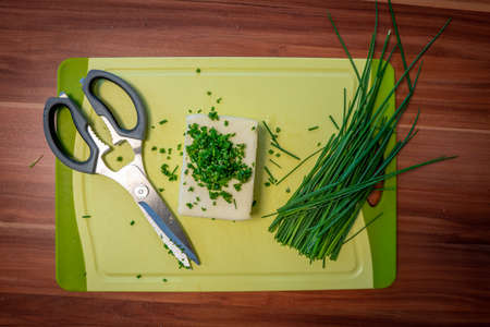 on a cutting board lie butter, chives and scissors to prepare herb butterの写真素材