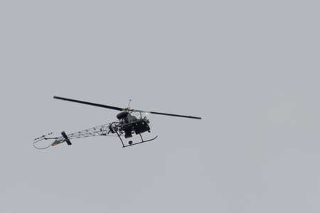 a small helicopter with tubular frame flies in the sky