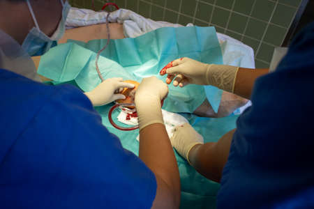 two doctors perform a hematoma removal with sterile gloves on a lower leg