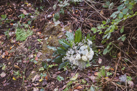 on a compost heap lies a thrown away white bunch of flowersの写真素材