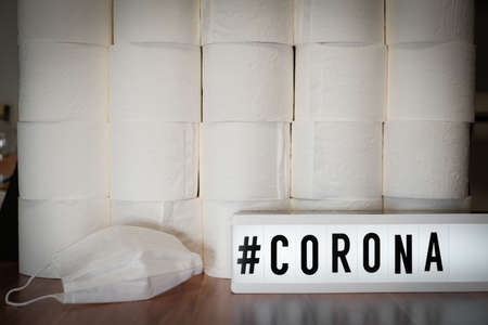 a sign with the inscription #Corona stands before a wall of toilet paper rolls