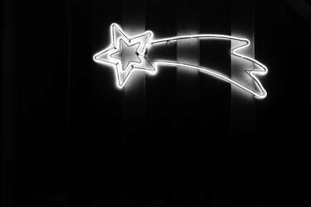 on a wooden wall hangs a Christmas illumination in the form of a star