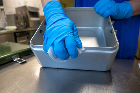 a member of an operating department cleans instrument containers with a cleaning cloth