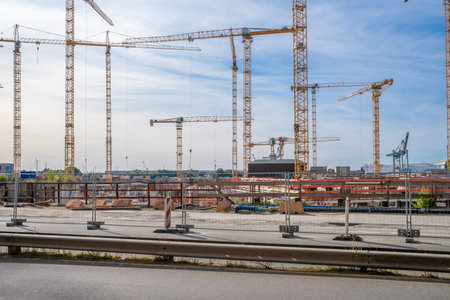 on a large construction site there are many yellow construction cranes and the sky is blueのeditorial素材