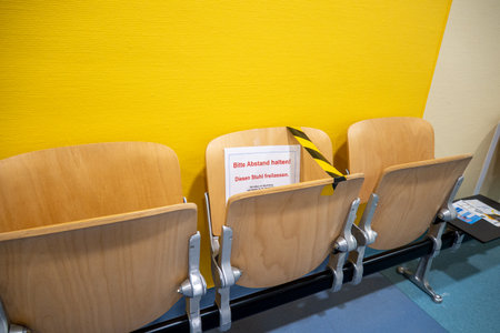 In a hospital corridor chairs are blocked with adhesive tape because of Coronaの写真素材