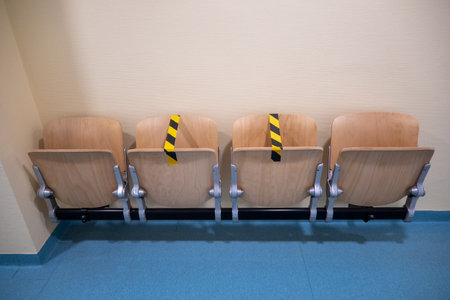 In a hospital corridor chairs are blocked with adhesive tape because of Coronaの写真素材