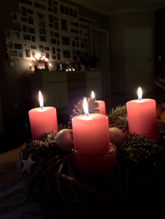a close up of a burning red candle and the background is dark