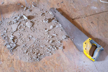 on the floor of a construction site lies a saw and trash