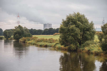 nuclear power plant stands next to a wide river and white smoke rises from the cooling towersの写真素材