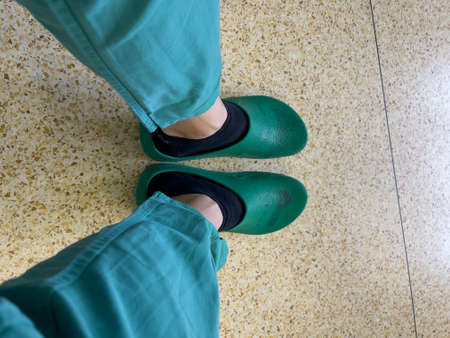 a picture of the stretched legs in green surgical clothing and surgical shoes