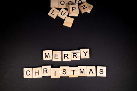 The words merry Christmas were placed on a dark background with wooden letters