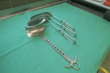 various surgical abdominal retractors lie side by side on a green base