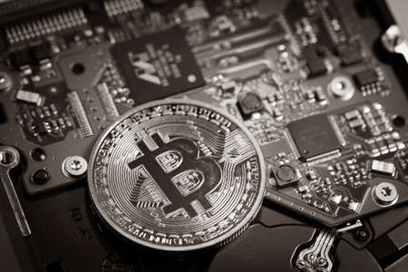 one bitcoin coin lies on a computer boardの写真素材