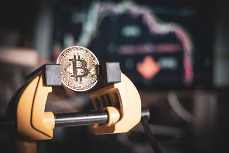 a bitcoin coin is clamped in a viceの写真素材