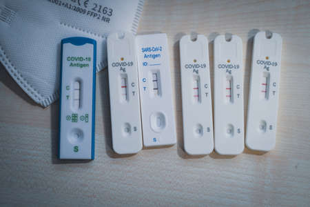 6 positive corona rapid tests lie next to a medical face mask