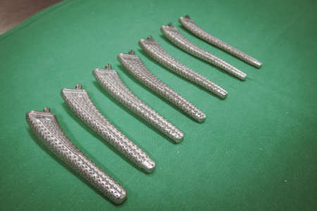some surgical rasps of different sizes for a transfemoral prosthesis lie on a green surgical drape