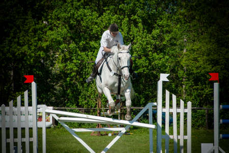 a rider jumps over an obstacle with his horse