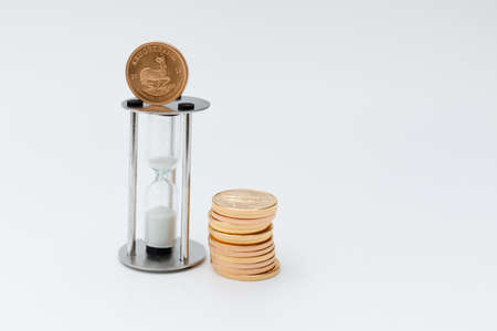 some gold coins stand next to an hourglass