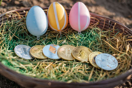 different crypto coins lie next to each other in an easter basket together with easter eggsの写真素材