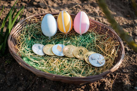 different crypto coins lie next to each other in an easter basket together with easter eggsの写真素材