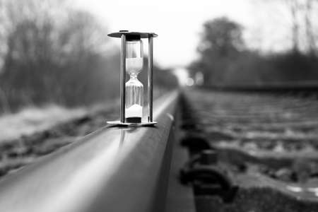 an hourglass stands on the rails of the railroadの写真素材