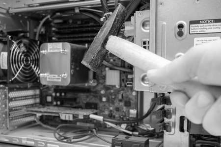 a hammer is held in front of an unscrewed PC