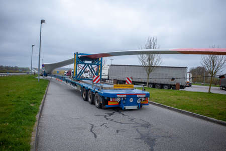 the wing of a wind turbine lies on a trailer on the highway