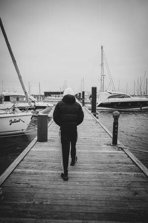 a young man walks along the harbor in overcast weatherのeditorial素材