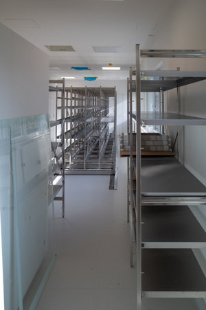 in a storage room for sterile instruments stands a new empty metal shelf