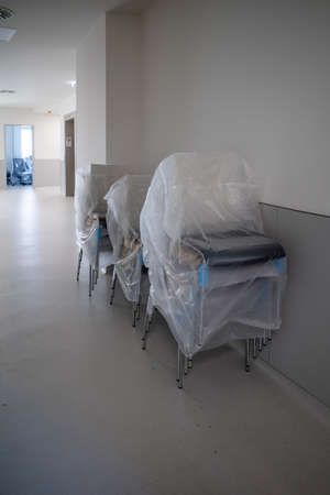 many chairs are stacked and covered with foil in a hallwayの写真素材