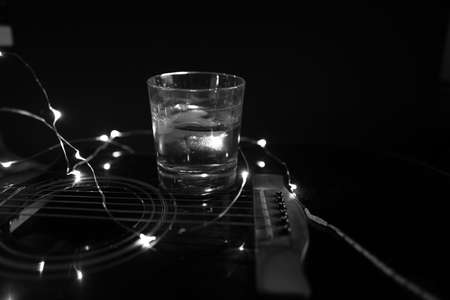 on a guitar is a glass of whiskey with ice cubes in black whiteの写真素材