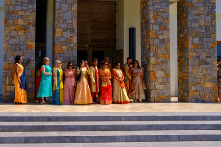 in front of the hotel a colorfully dressed indian wedding party is waiting for the arrival of the bride and groomのeditorial素材